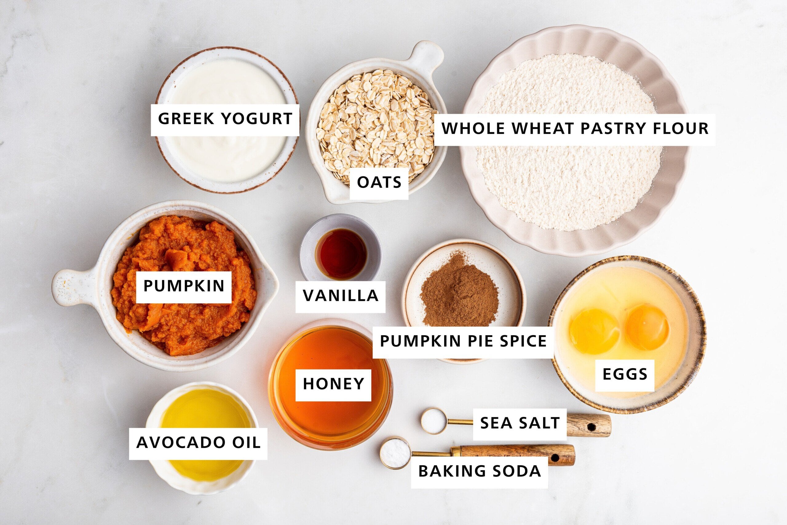 Ingredients measured out to make Healthy Pumpkin Muffins: whole wheat pastry flour, eggs, sea salt, baking soda, pumpkin pie spice, oats, vanilla, honey, Greek yogurt, pumpkin and avocado oil.