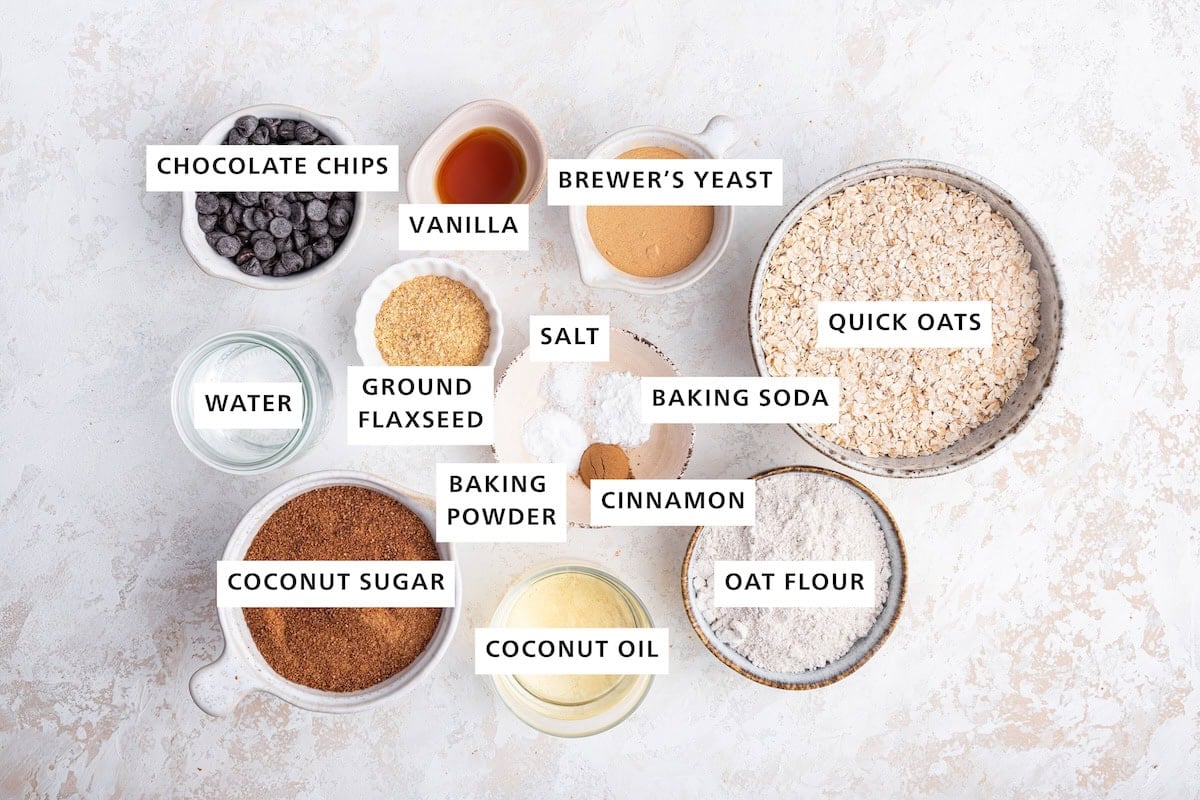 Ingredients measured out to make Healthy Lactation Cookies: quick oats, oat flour, brewer's yeast, baking soda, cinnamon, coconut oil, sea salt, baking powder, vanilla, ground flaxseed, chocolate chips, water and coconut sugar.