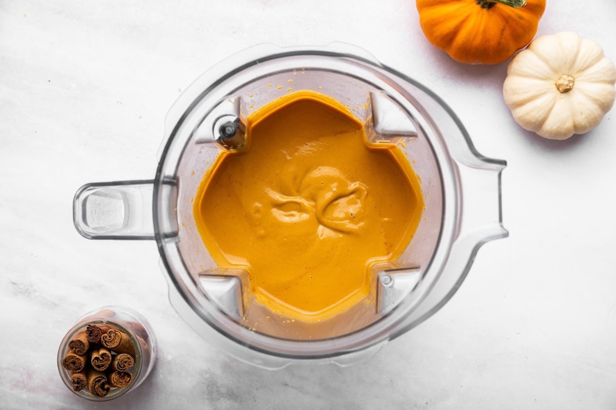 Smooth orange pumpkin mixture in a blender pitcher.