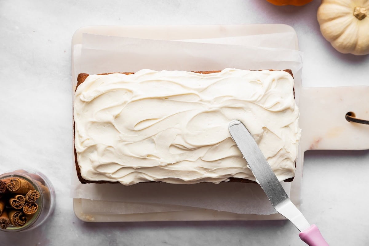 Cottage cheese frosting spread over pumpkin protein bread with an offset spatula.