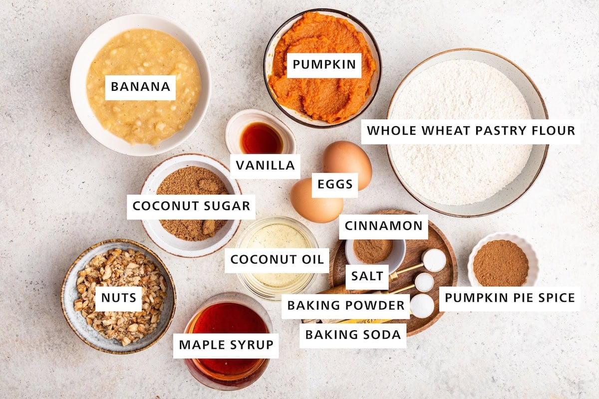 Ingredients measured out to make Pumpkin Banana Bread: whole wheat pastry flour, baking powder, pumpkin pie spice, baking soda, cinnamon, sea salt, vanilla, pumpkin, eggs, maple syrup, coconut sugar and coconut oil.