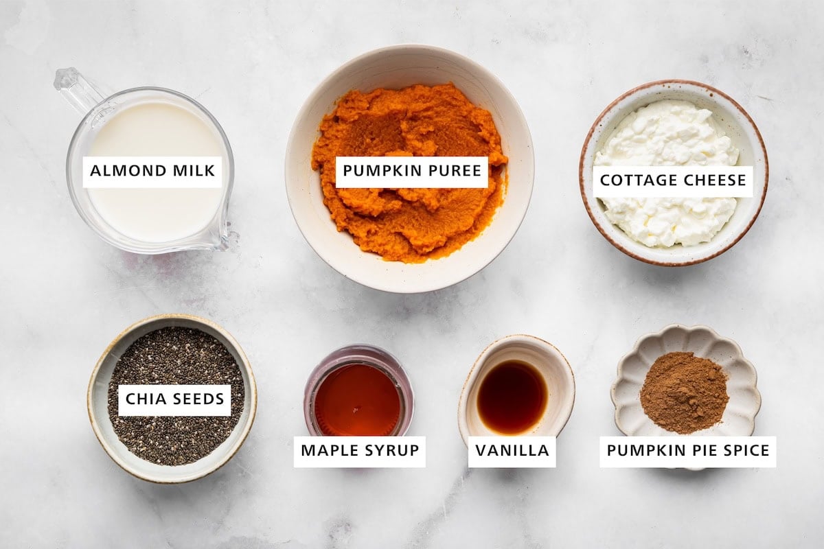 Ingredients measured out for pumpkin mousse include: almond milk, pumpkin puree, cottage cheese, pumpkin pie spice, vanilla, maple syrup, and chia seeds.
