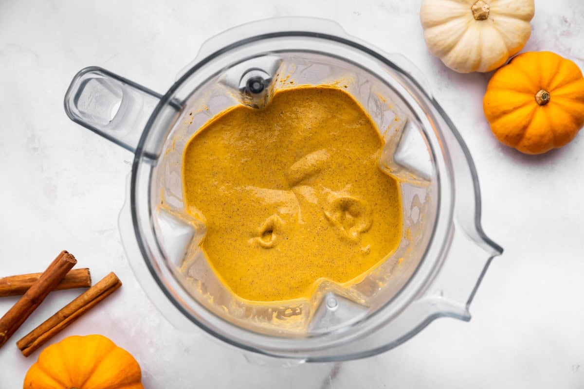 Smooth orange pumpkin mousse in a blender pitcher after blending.