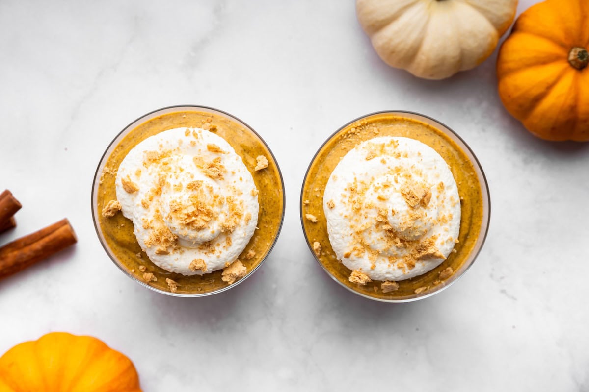 Overhead view of pumpkin mousse divided between two glasses and topped with whipped topping and graham cracker crumbs.
