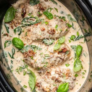 Overhead view of slow cooker marry me chicken topped with Parmesan and fresh basil.