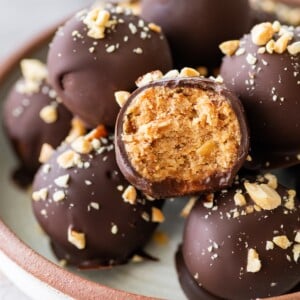 Snickers protein ball cut in half to reveal its chewy peanut butter and date center beneath a dark chocolate coating.