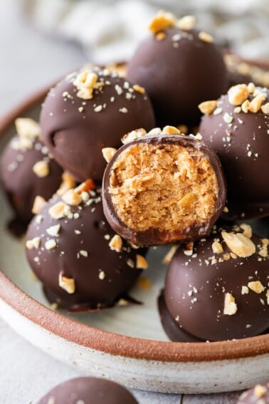 Snickers protein ball cut in half to reveal its chewy peanut butter and date center beneath a dark chocolate coating.