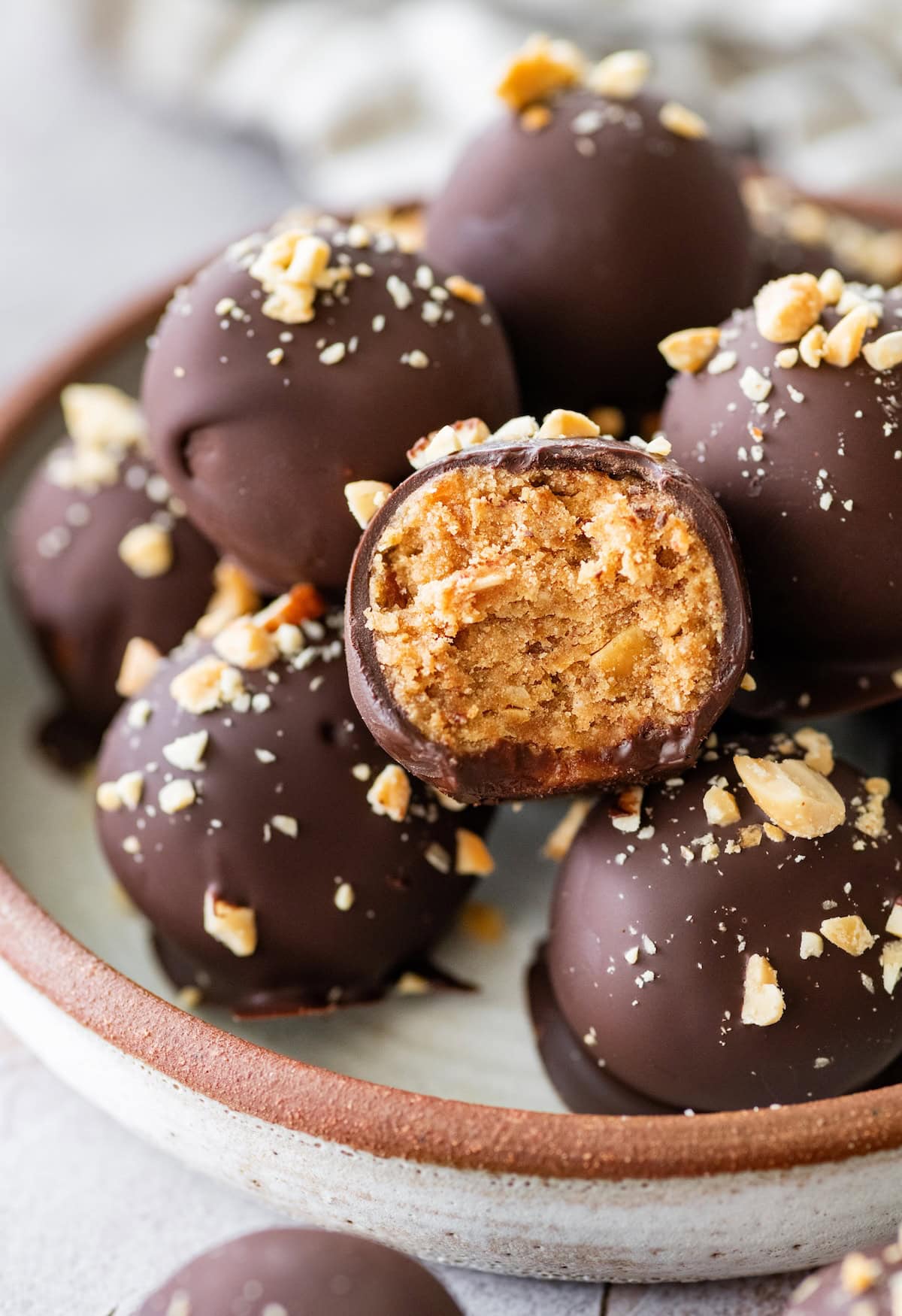 Snickers protein ball cut in half to reveal its chewy peanut butter and date center beneath a dark chocolate coating.